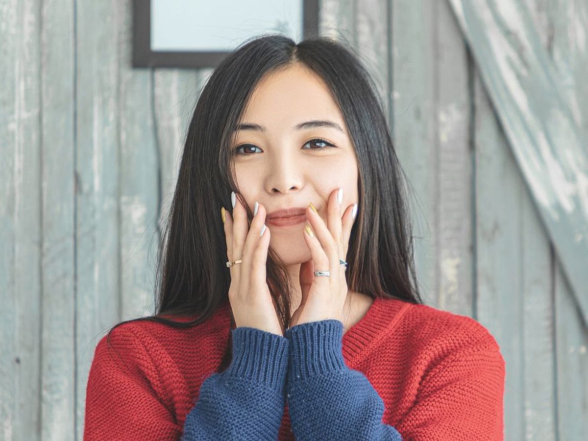 肌の調子がよく、両手で頬に触れて笑う女性